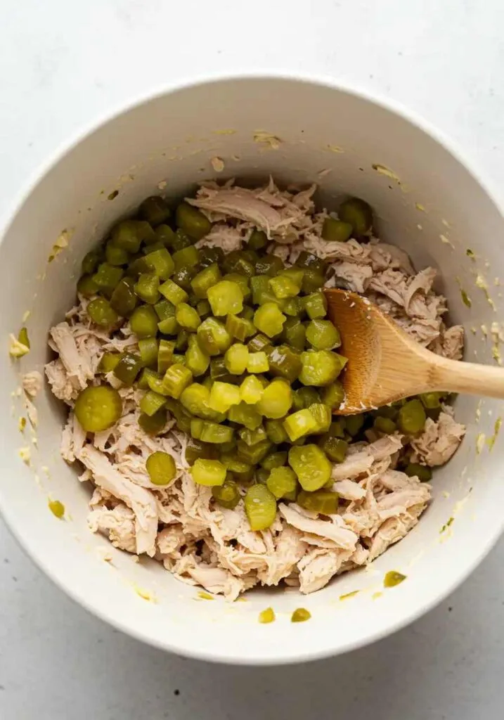 Mixing shredded chicken with pickles