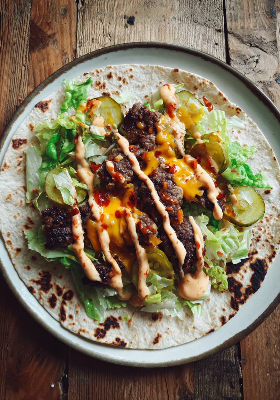 smash burger taco on grill with cheese and pickles